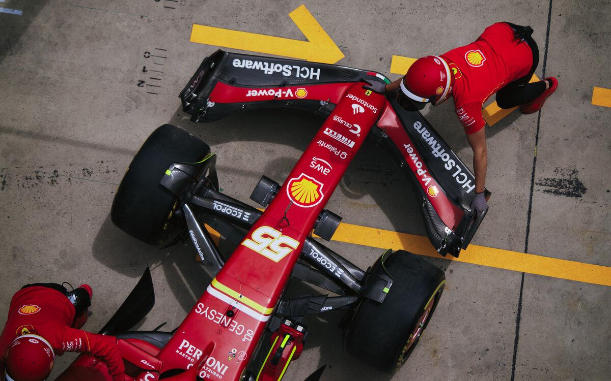 Carlos Sainz, predné krídlo Ferrari, mechanik zatláča monopost do garáže