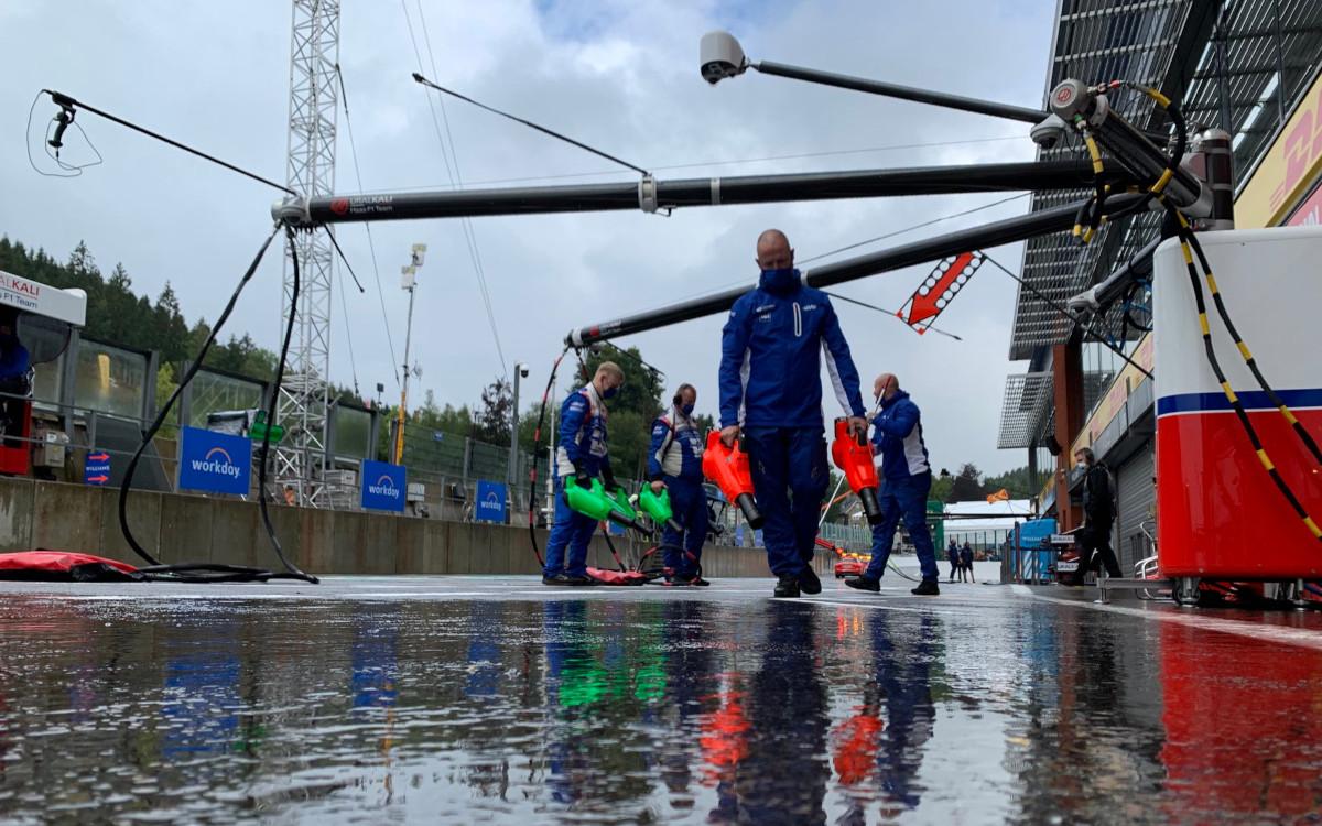 Mechanici Haasu fukármi sušia asfalt pred garážou, dážď