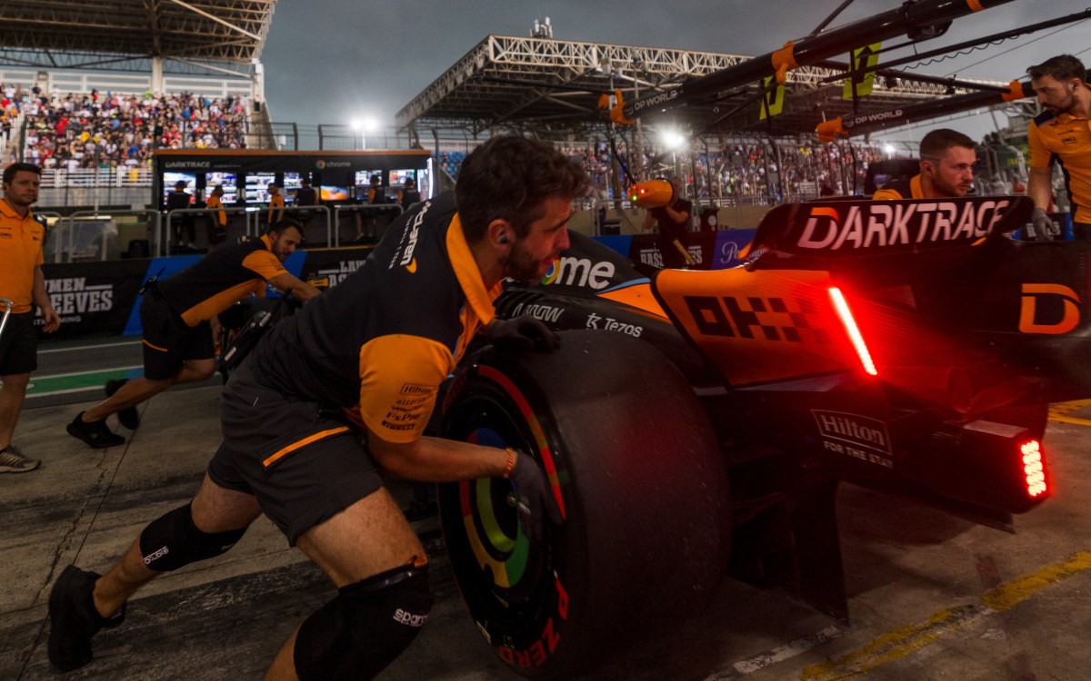 Mechanici McLarenu zatláčajú monopost Landa Norrisa do garáže